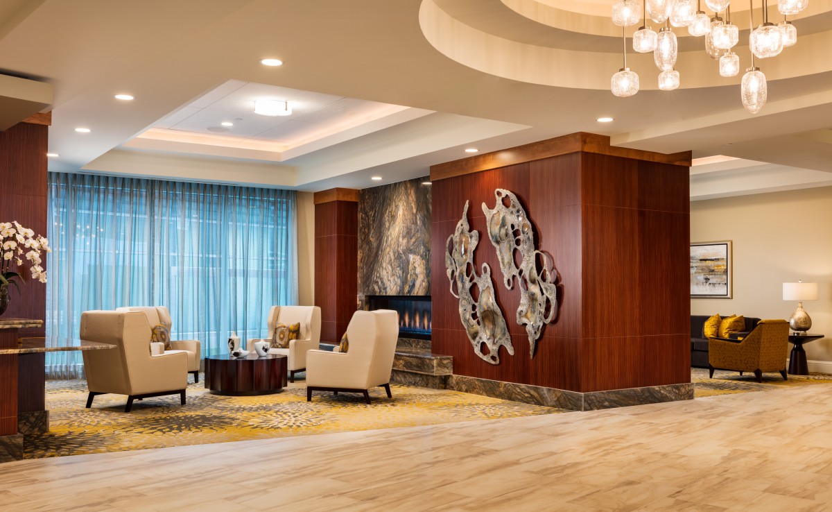 A modern lobby area featuring comfortable seating, elegant wood paneling, and decorative artwork on the walls.