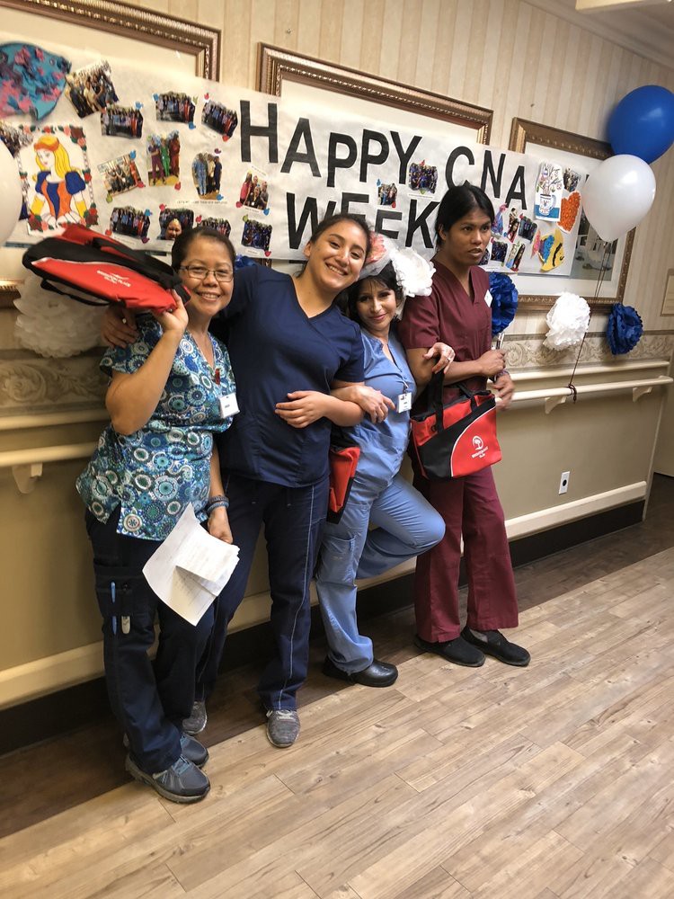 Healthcare workers celebrate CNA Week with a group photo in front of a decorated wall.