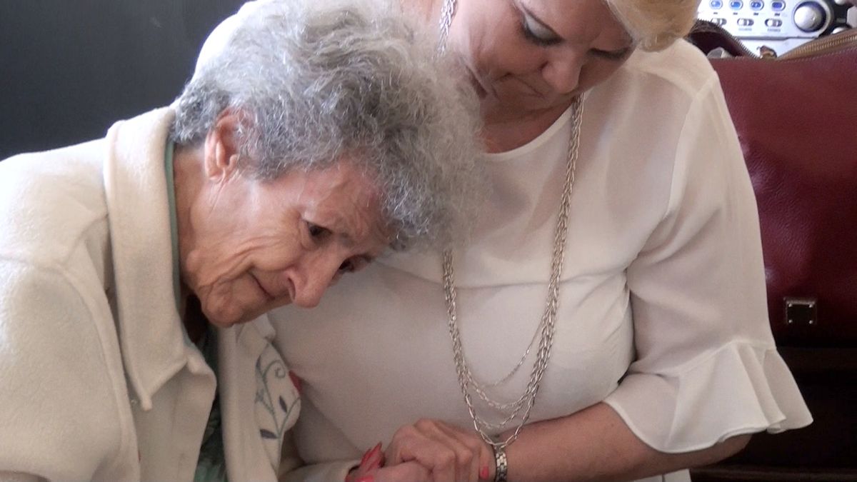 Two women share a comforting moment, holding hands with care and compassion.