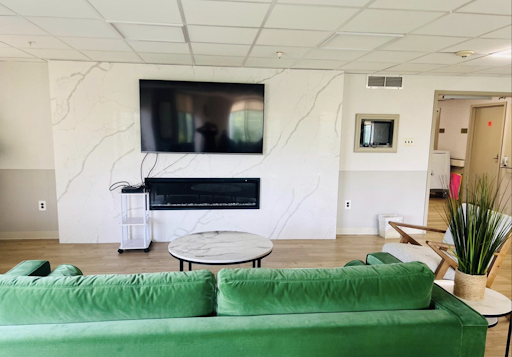 A modern living room featuring a green sofa, a television mounted on the wall, and a stylish coffee table.