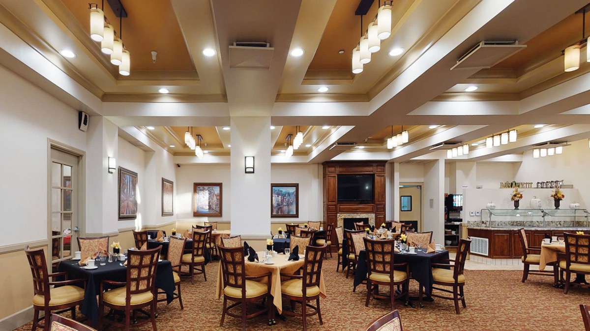 A cozy restaurant dining area featuring neatly arranged tables and chairs under warm lighting.