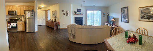 A cozy living room with a curved sofa facing a fireplace and sliding glass doors opening to the outside.