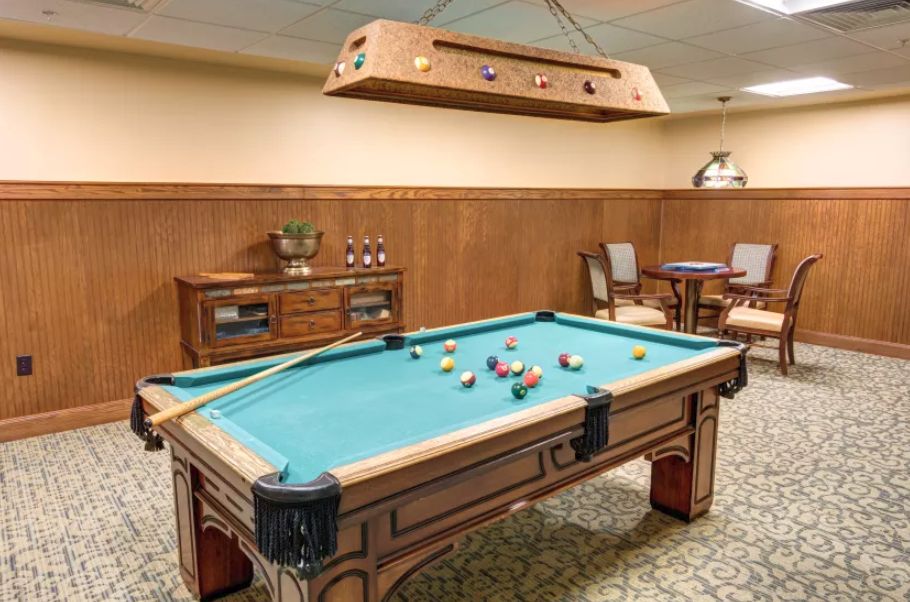 A luxurious game room featuring a billiards table and classic wooden furniture.