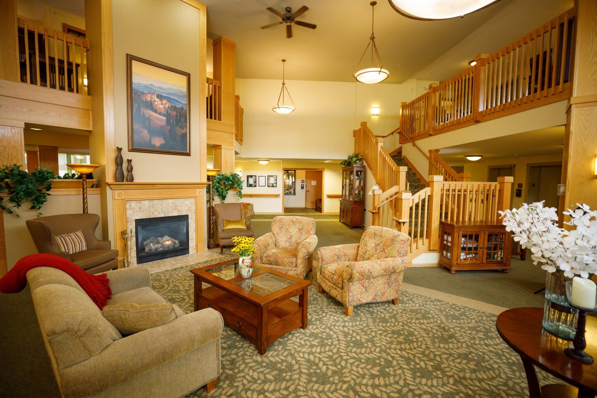A cozy living room with comfortable seating, a fireplace, and an elegant staircase.