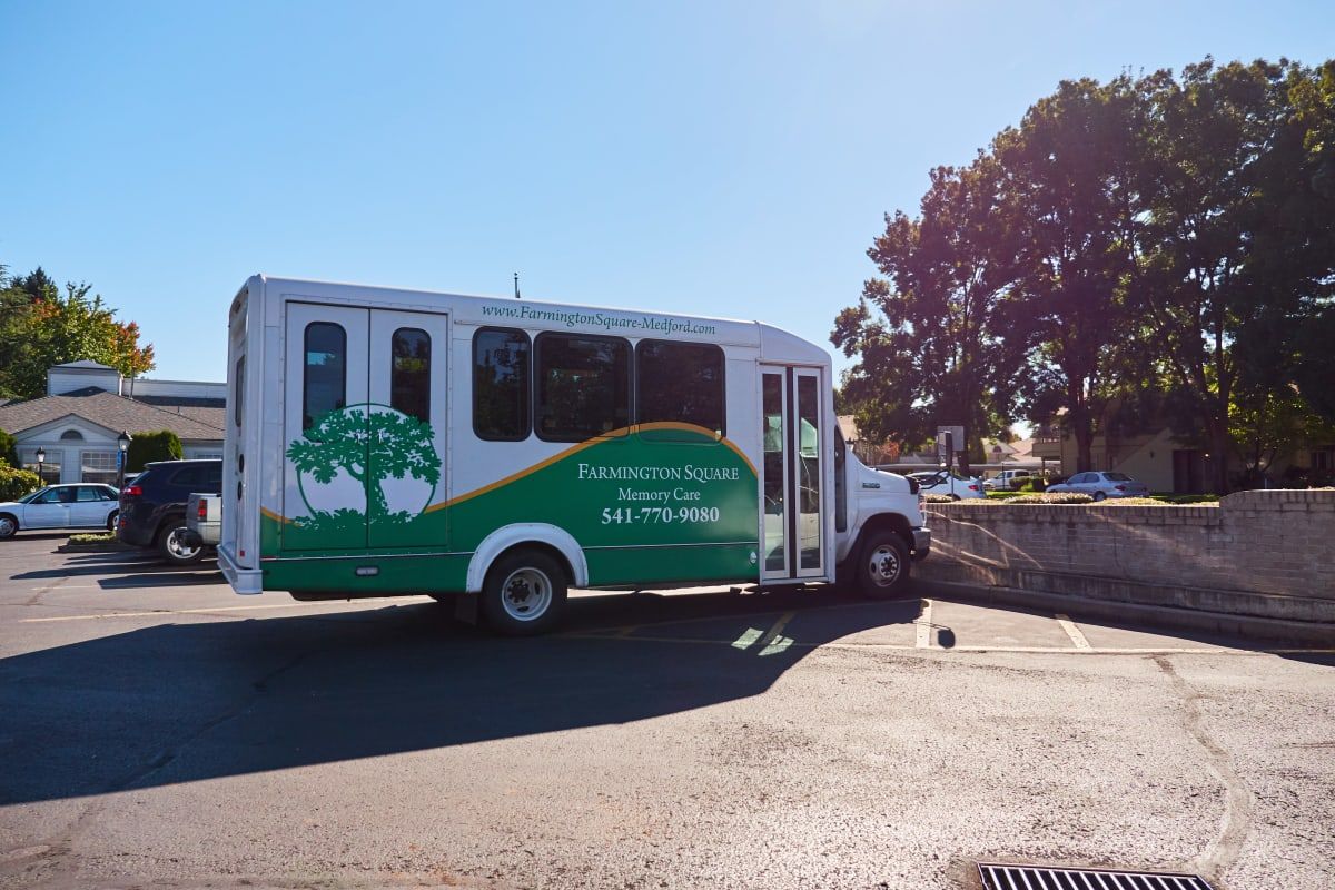 A green and white bus parked outdoors on a sunny day.