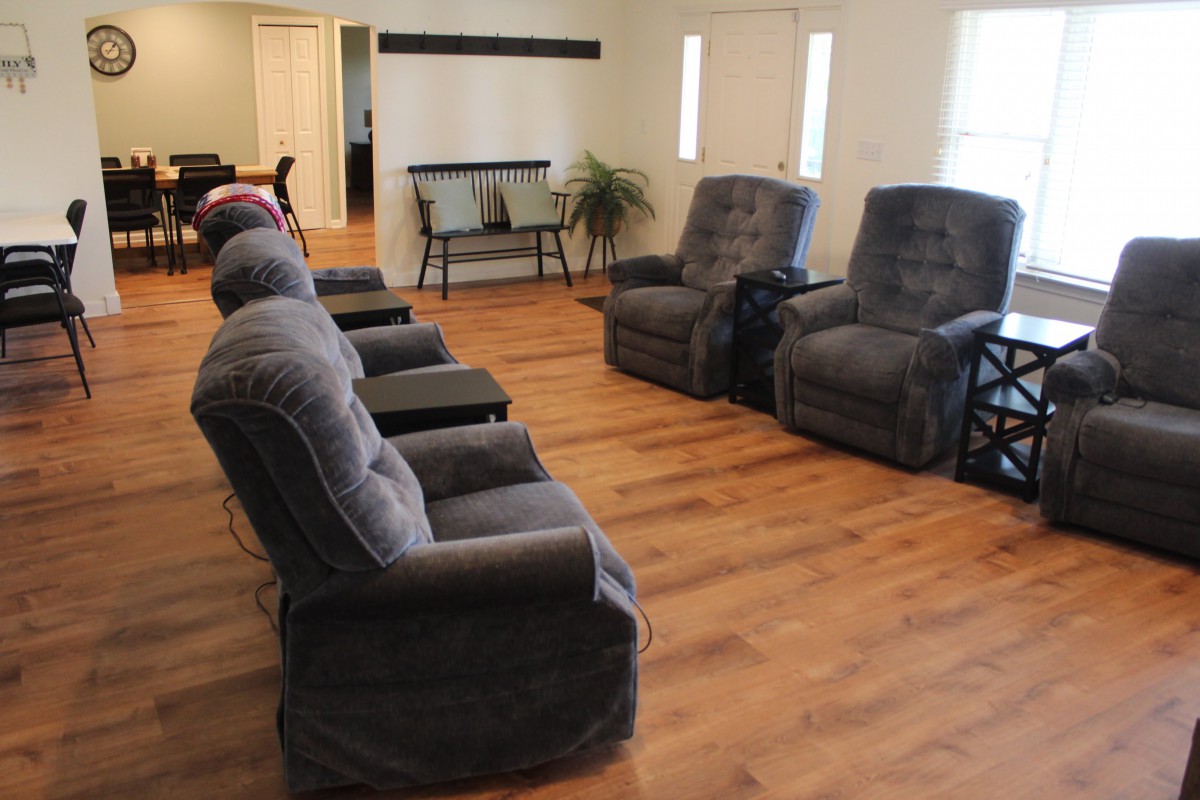 A cozy living room with multiple recliner chairs arranged on a wooden floor.