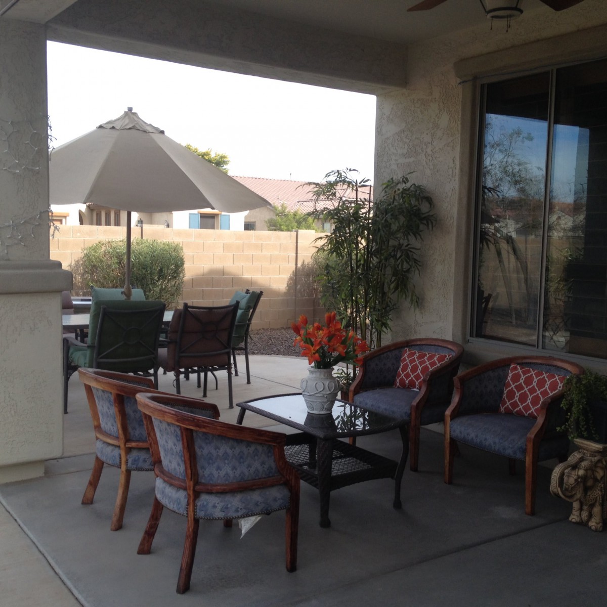 A cozy outdoor patio with seating and a table under a shaded umbrella.