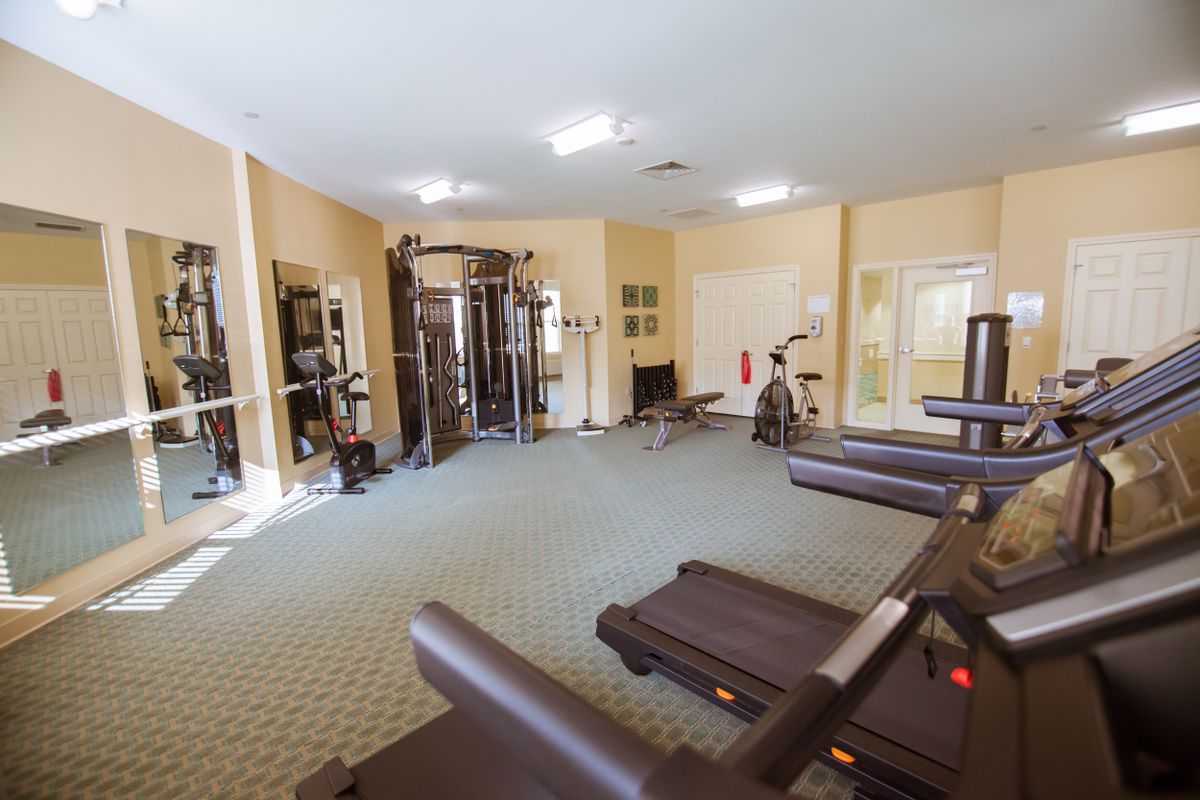 A spacious gym with various exercise equipment including treadmills and weights.