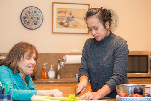 Two women sharing a joyful moment while preparing food together in the kitchen.