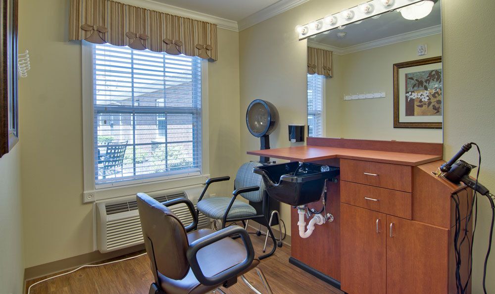 An interior view of a hair salon with chairs, a mirror, and a hairdryer station.