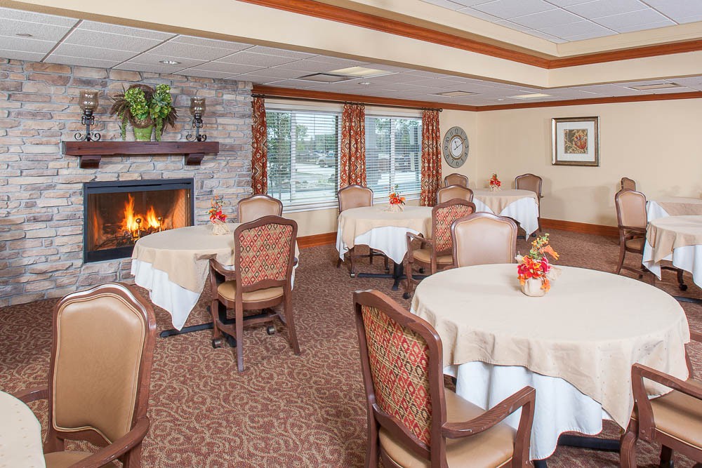 A cozy dining room with round tables and a fireplace, featuring elegant decor.