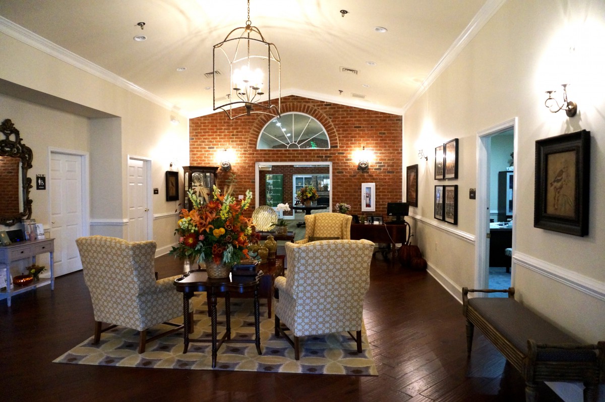 A cozy living room with elegant furniture, a brick accent wall, and a chandelier.
