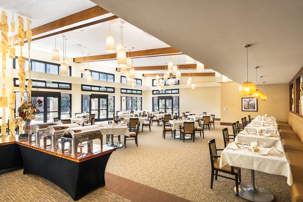 An elegant and spacious dining area with neatly arranged tables and chairs, well-lit by natural light from large windows.