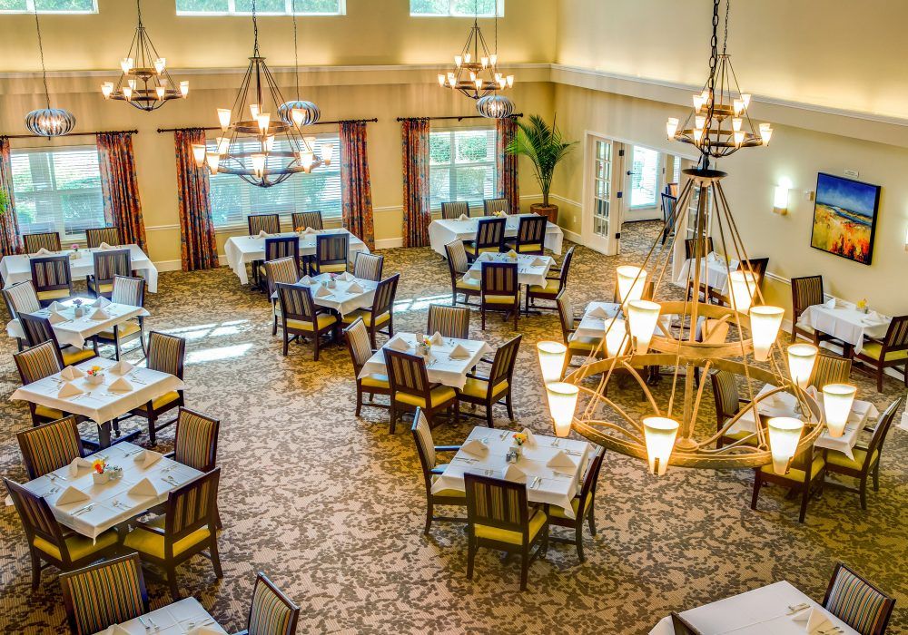 An elegant restaurant dining room with neatly arranged tables and stylish chandeliers.