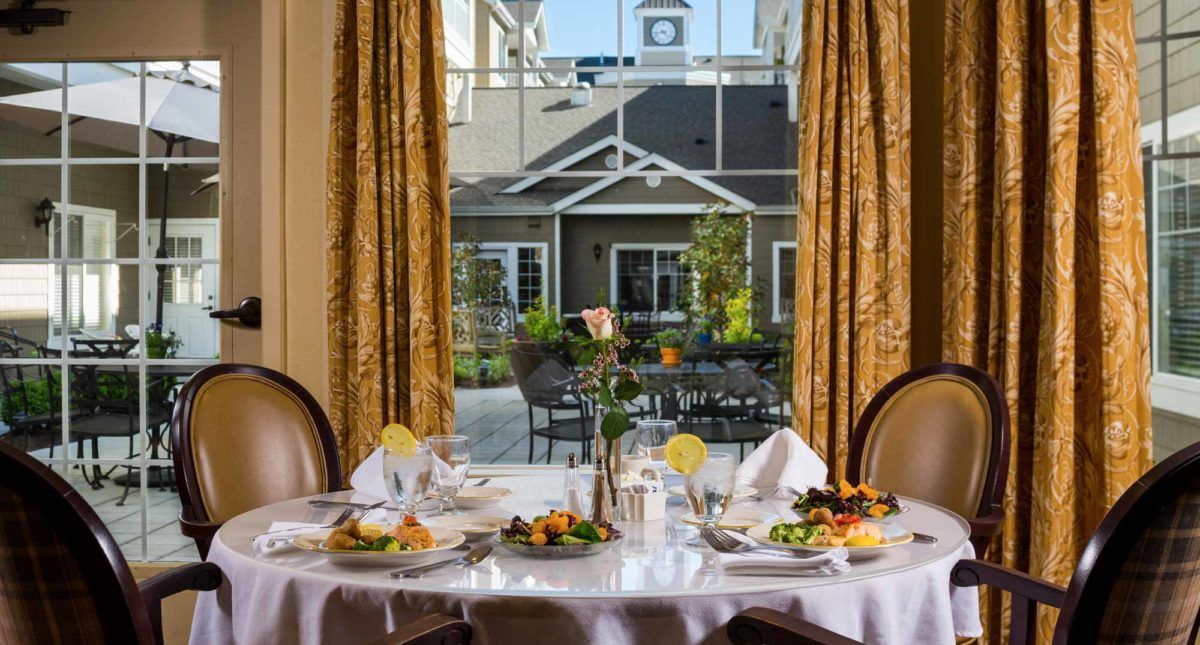 An elegantly set dining table with a view of an outdoor courtyard.