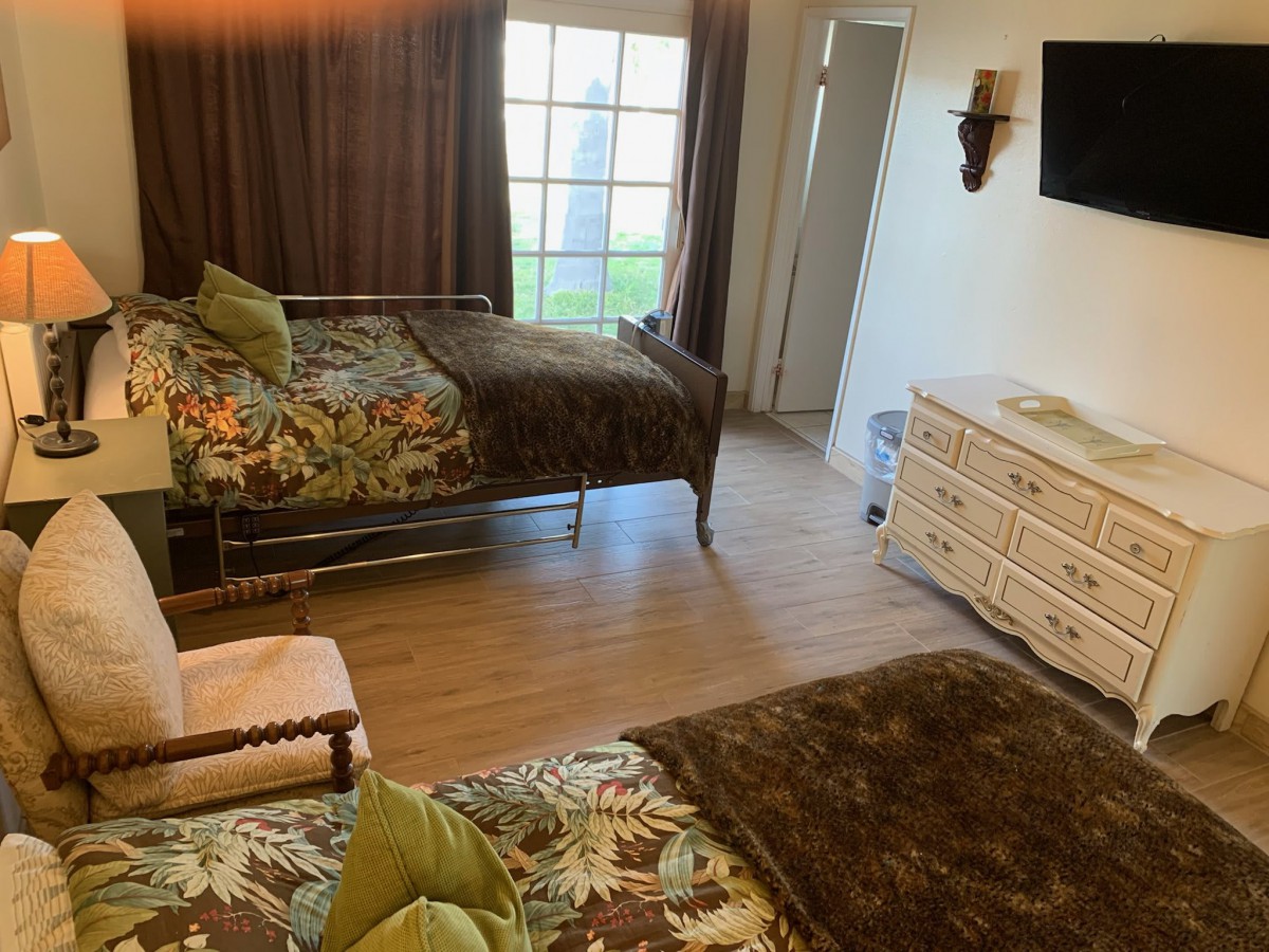A cozy bedroom with two beds, a dresser, and a television.