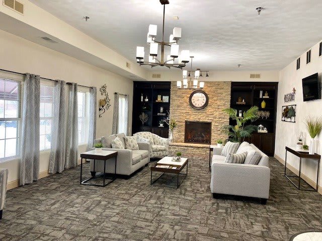 A modern living room with comfortable sofas, a central fireplace, decorative shelves, and elegant lighting.