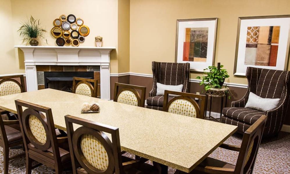 A well-decorated conference room featuring a large meeting table, comfortable chairs, wall art, and a cozy fireplace.