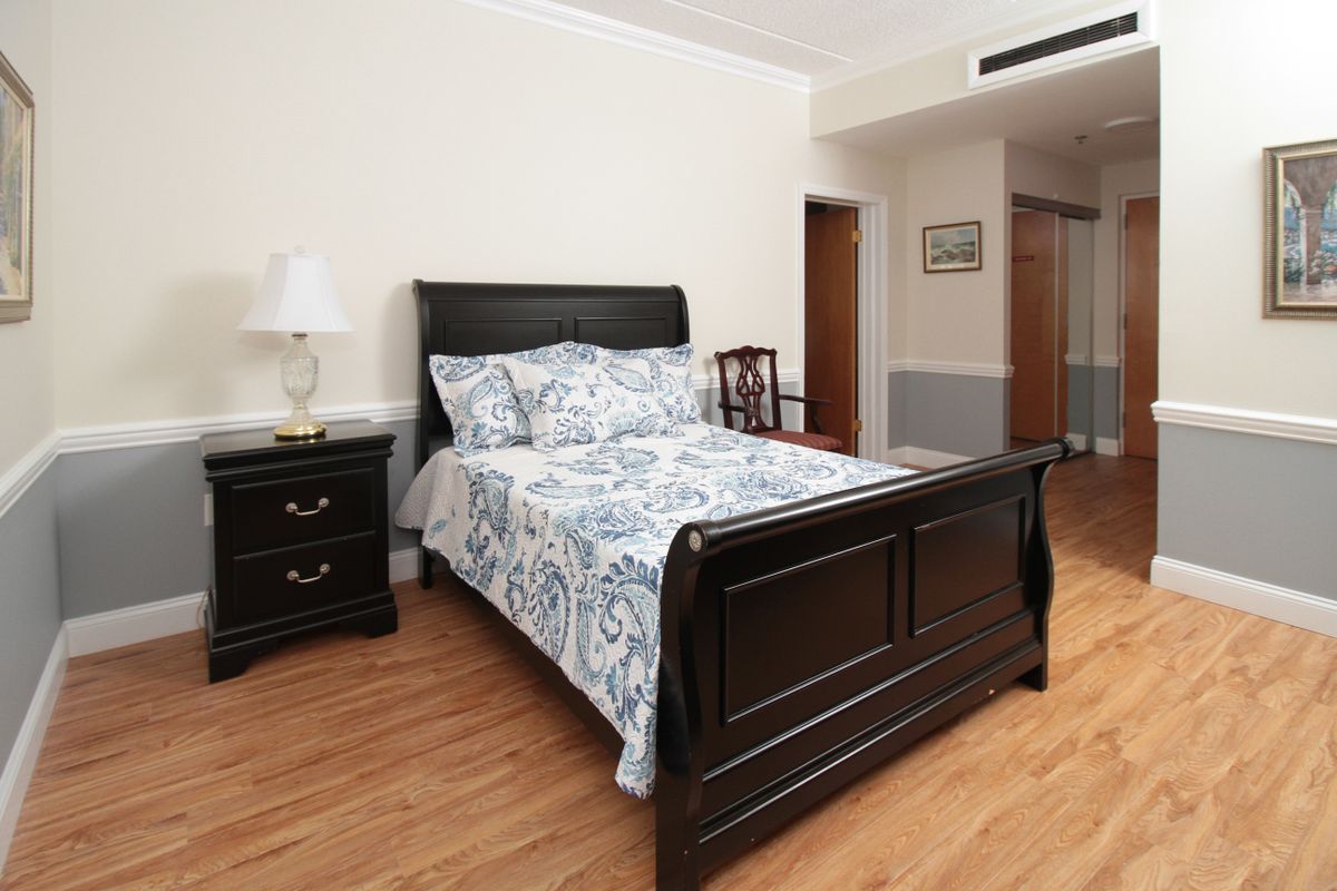 A cozy bedroom with a dark wooden bedframe and matching nightstand, featuring a lamp and patterned bedding.