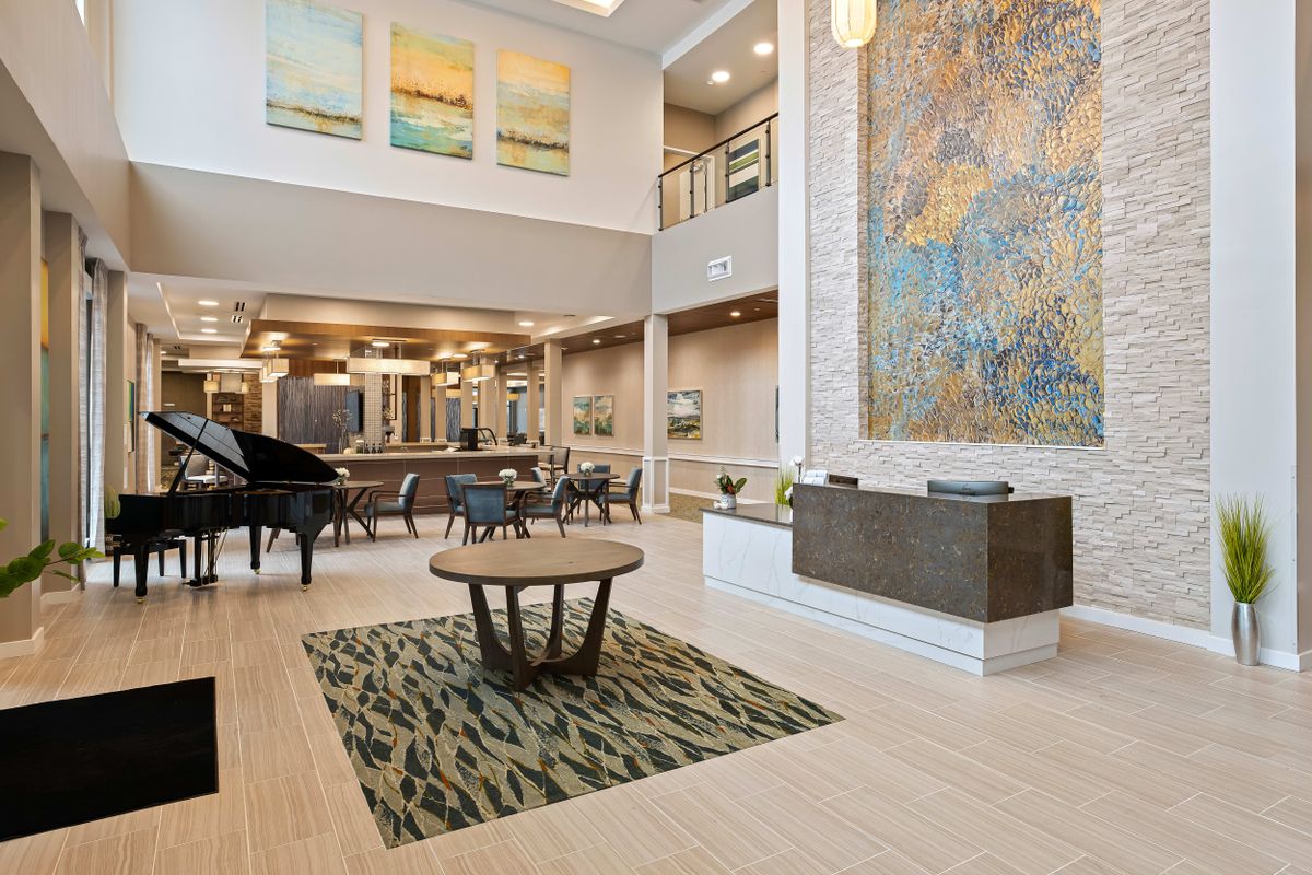 A modern and elegantly designed lobby featuring a piano, large artwork, and a reception desk.