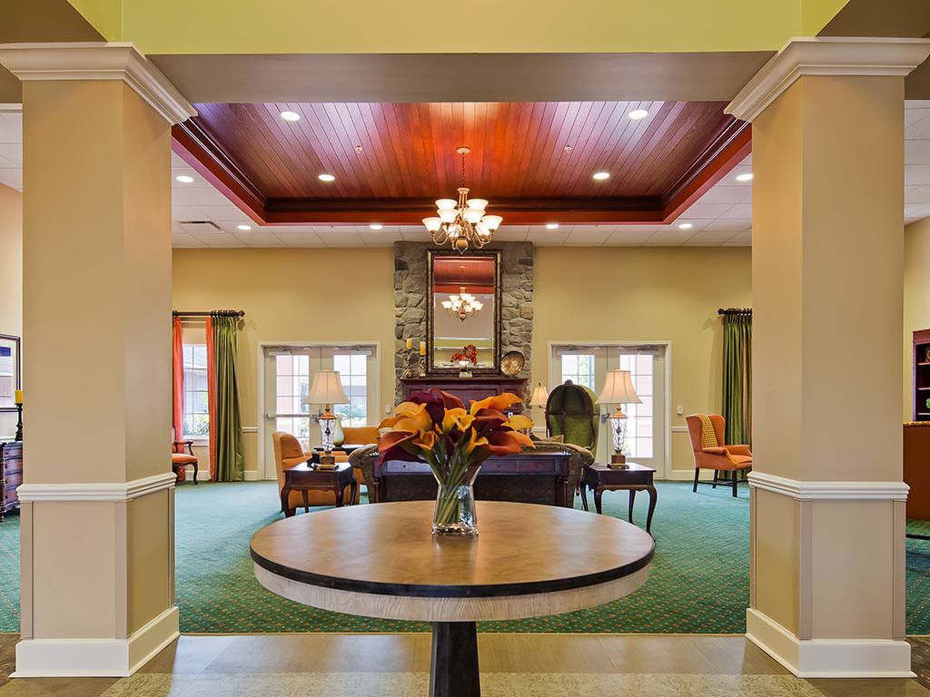 Elegant lobby with a centerpiece table, chandelier, and a cozy seating area near the fireplace.