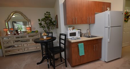 A compact kitchen and dining area with modern amenities, including a microwave, sink, and a small round table with chairs.