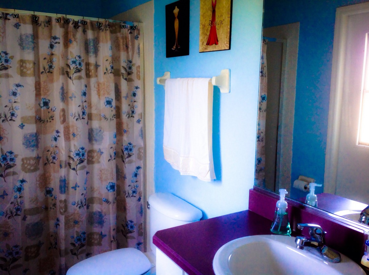 A vibrant bathroom with a purple countertop and floral shower curtain.