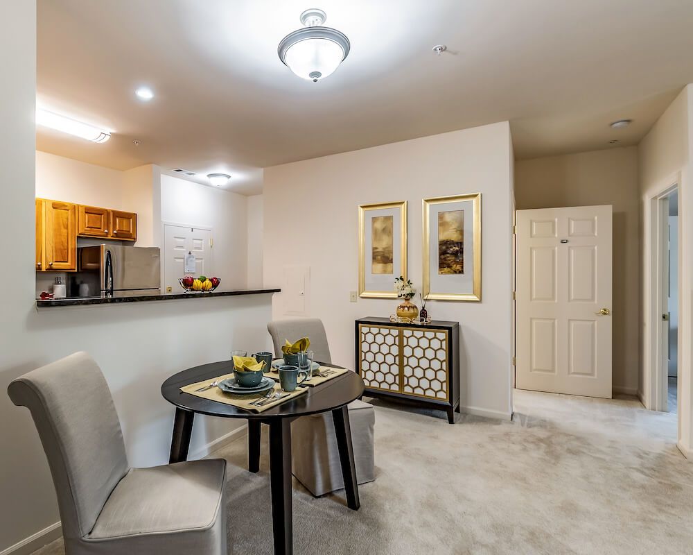 A modern dining area with a small table set, contemporary decor, and adjacent kitchen space.