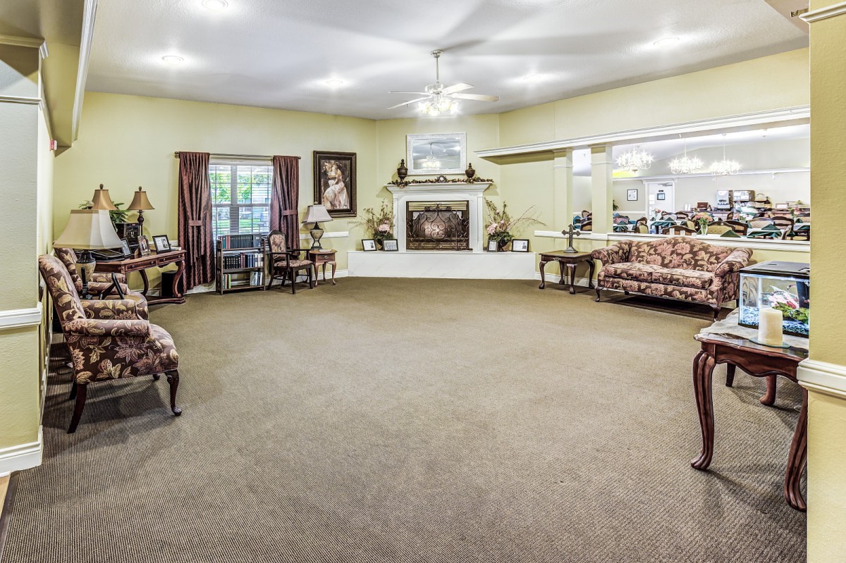 A spacious living room with carpeted floor, featuring sofas, a fireplace, and wall decor.