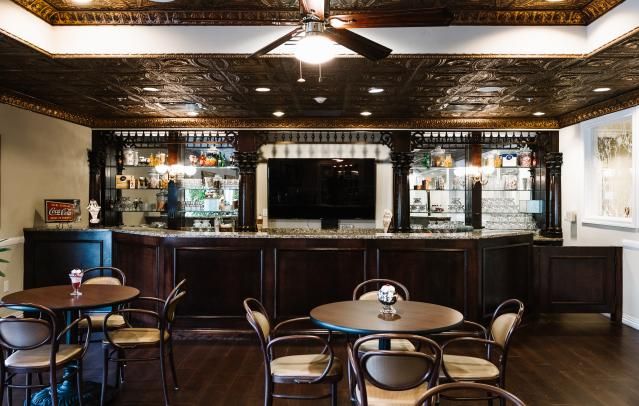 A cozy bar interior with dark wood furnishings, featuring a central counter and seating area.
