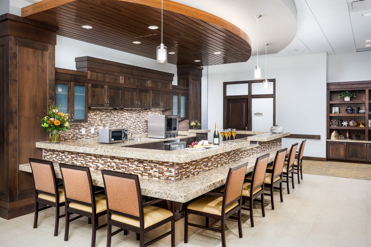 A modern kitchen with an elegant island counter and seating, featuring wooden cabinetry and stylish pendant lighting.
