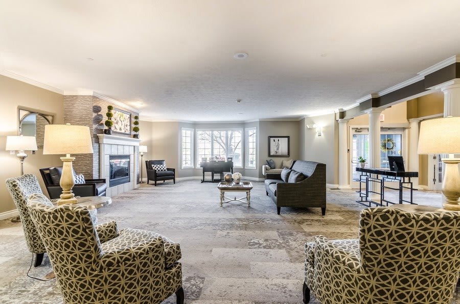 A spacious and modern living room with a fireplace, comfortable seating, and a large window.