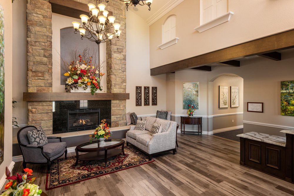 A modern living room featuring a cozy fireplace, elegant chandelier, and stylish furniture with wood flooring.