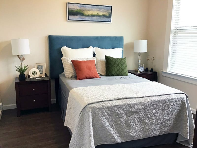 A modern bedroom with a neatly made bed, colorful pillows, and stylish decor.