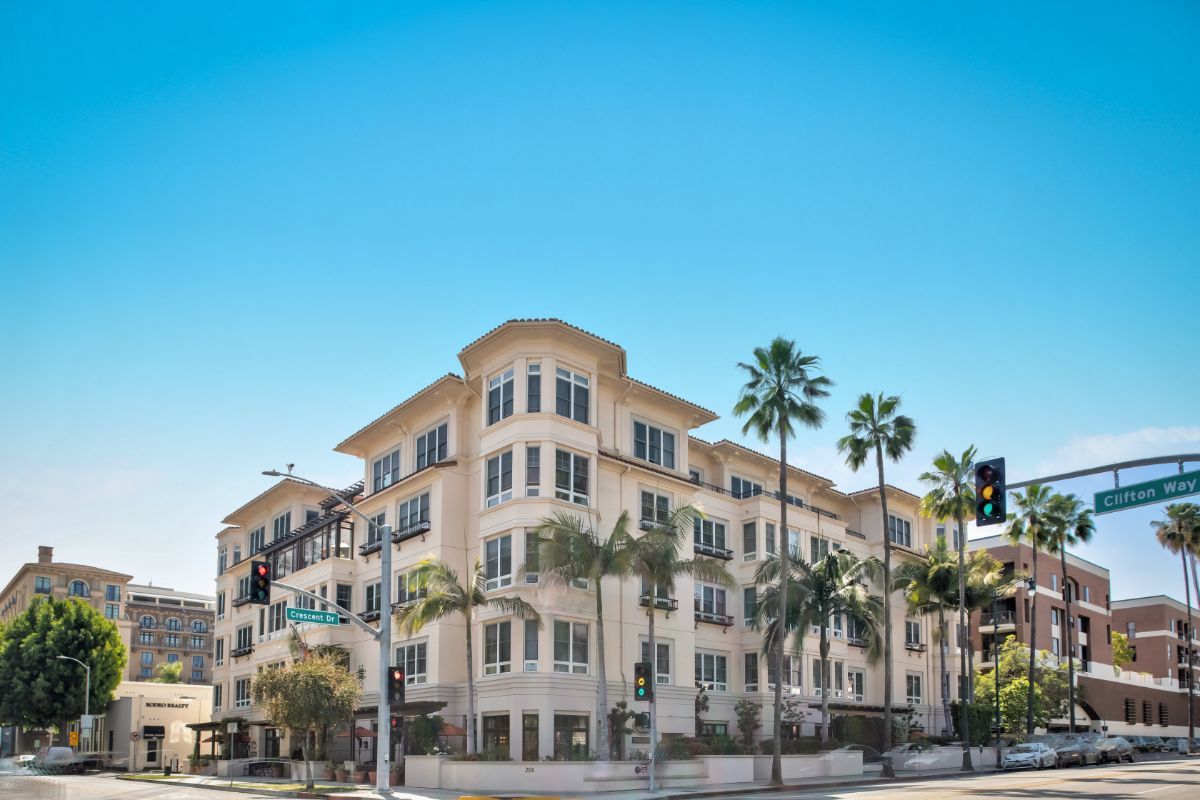 A residential apartment building surrounded by palm trees on a sunny day.