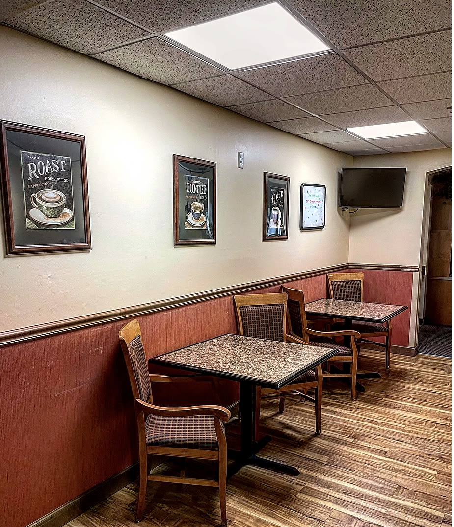 Interior of a cozy coffee shop with tables, chairs, and artwork on the walls.
