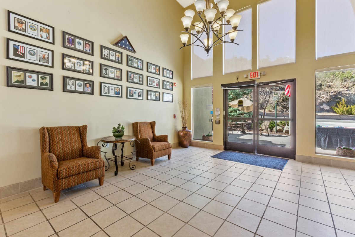 A well-lit lobby featuring comfortable seating, a chandelier, and framed pictures on the wall.