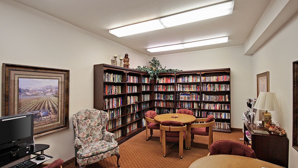 A cozy reading area with bookshelves, a table, and comfortable chairs.