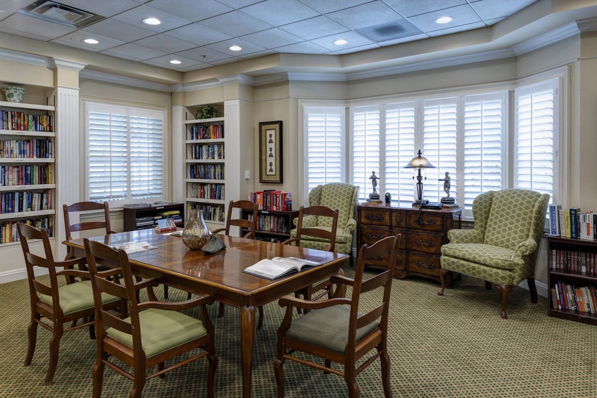 A cozy office meeting room with a wooden table, several chairs, and bookshelves in the background.