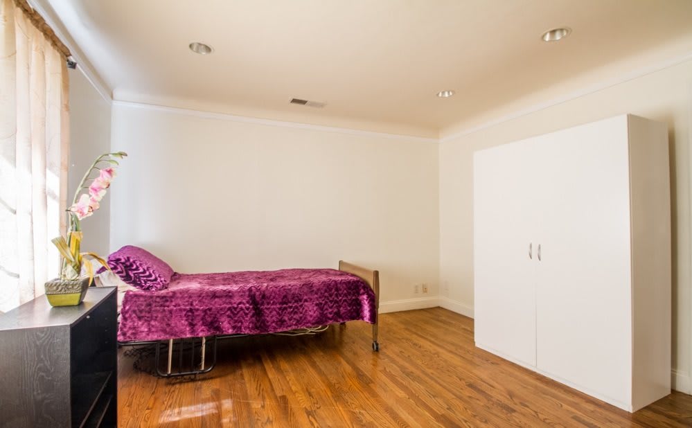 A minimalist bedroom with a single bed and hardwood flooring.