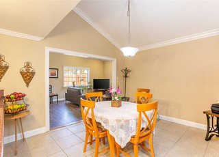 A cozy dining area with a table and chairs, featuring an open layout leading to a living room.