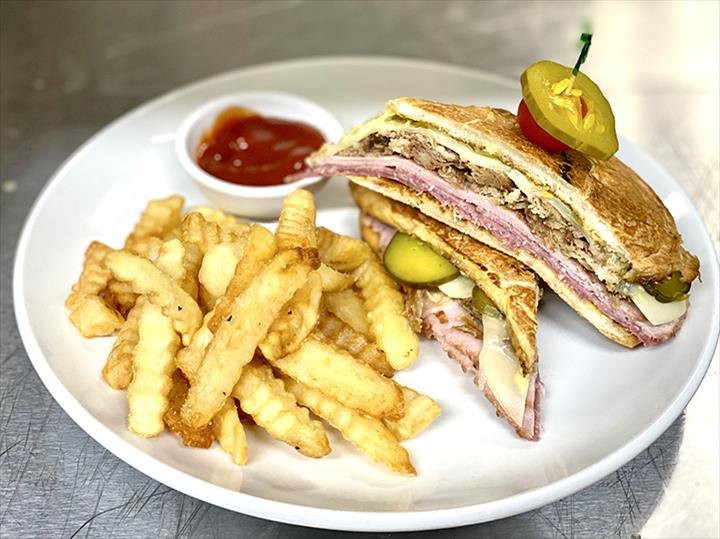 A delicious sandwich served with crinkle cut fries and a side of sauce.