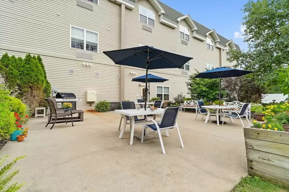 An outdoor patio area with tables, chairs, and umbrellas in front of a multi-story building.