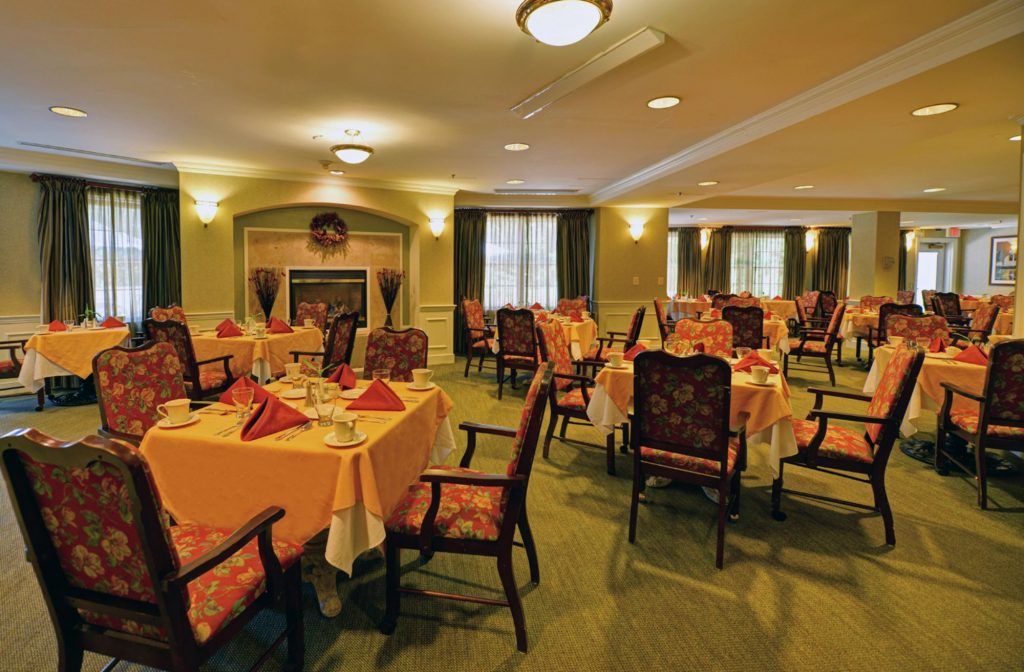 A cozy dining room with neatly arranged tables and chairs, featuring a warm fireplace.