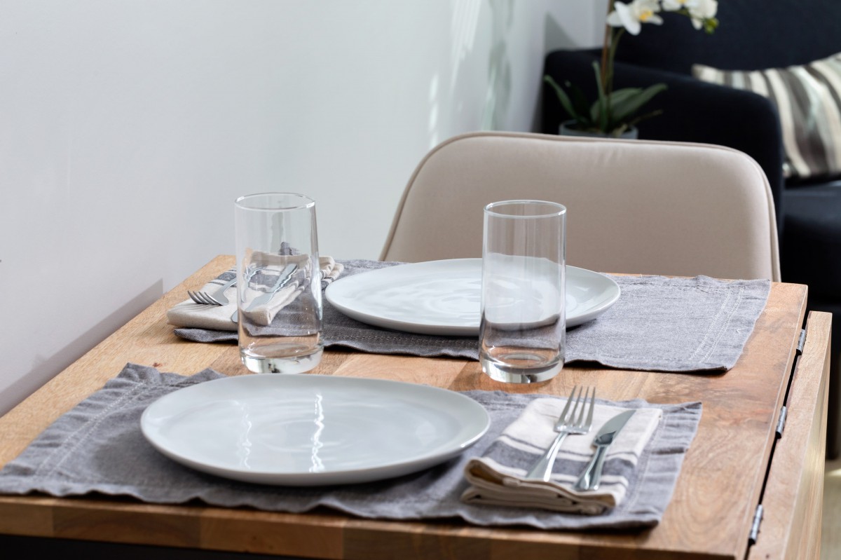 A neatly set dining table with plates, glasses, and cutlery.