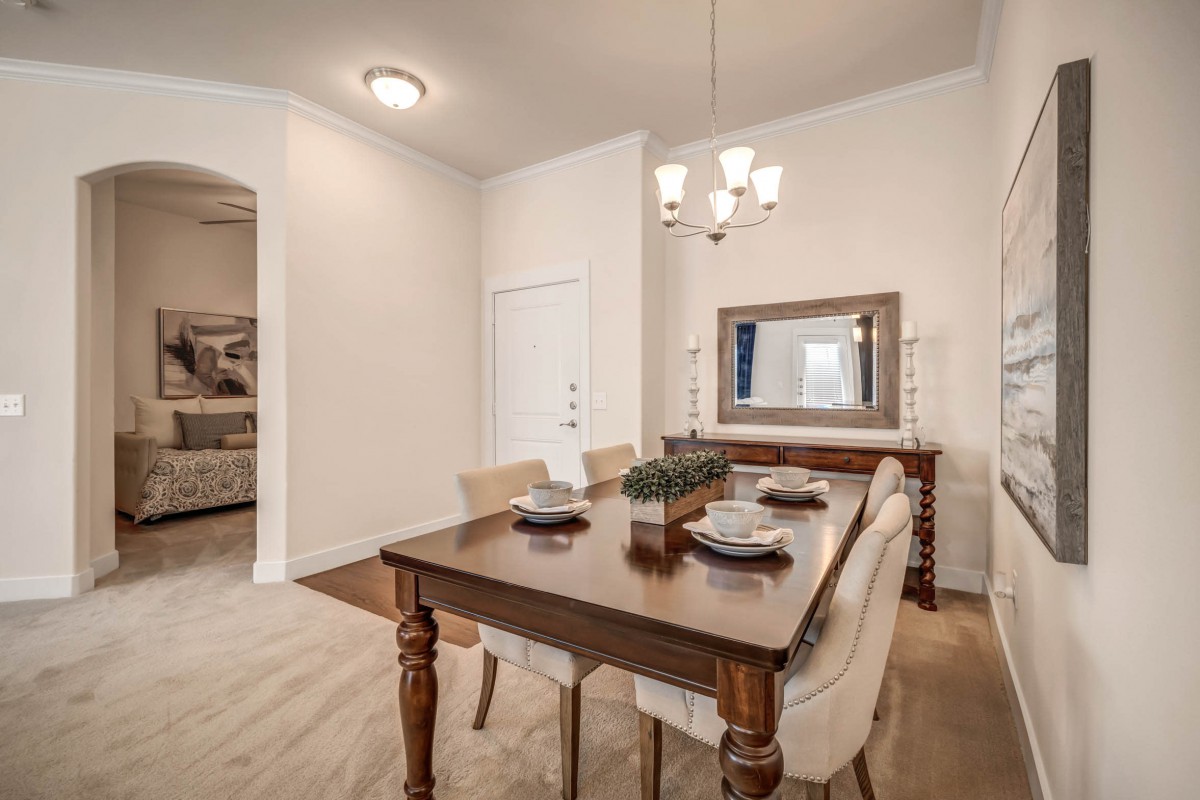 A neatly arranged dining room with a wooden table and chairs, illuminated by a chandelier.