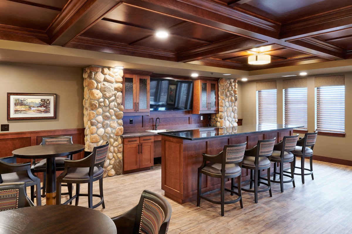 A modern bar interior with wooden furniture, stone accents, and cozy lighting.
