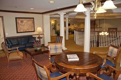 A cozy living room interior with a round wooden table, chairs, couches, and decorative columns.