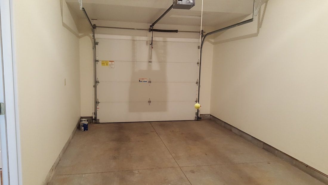 An empty garage with a closed door and a concrete floor.