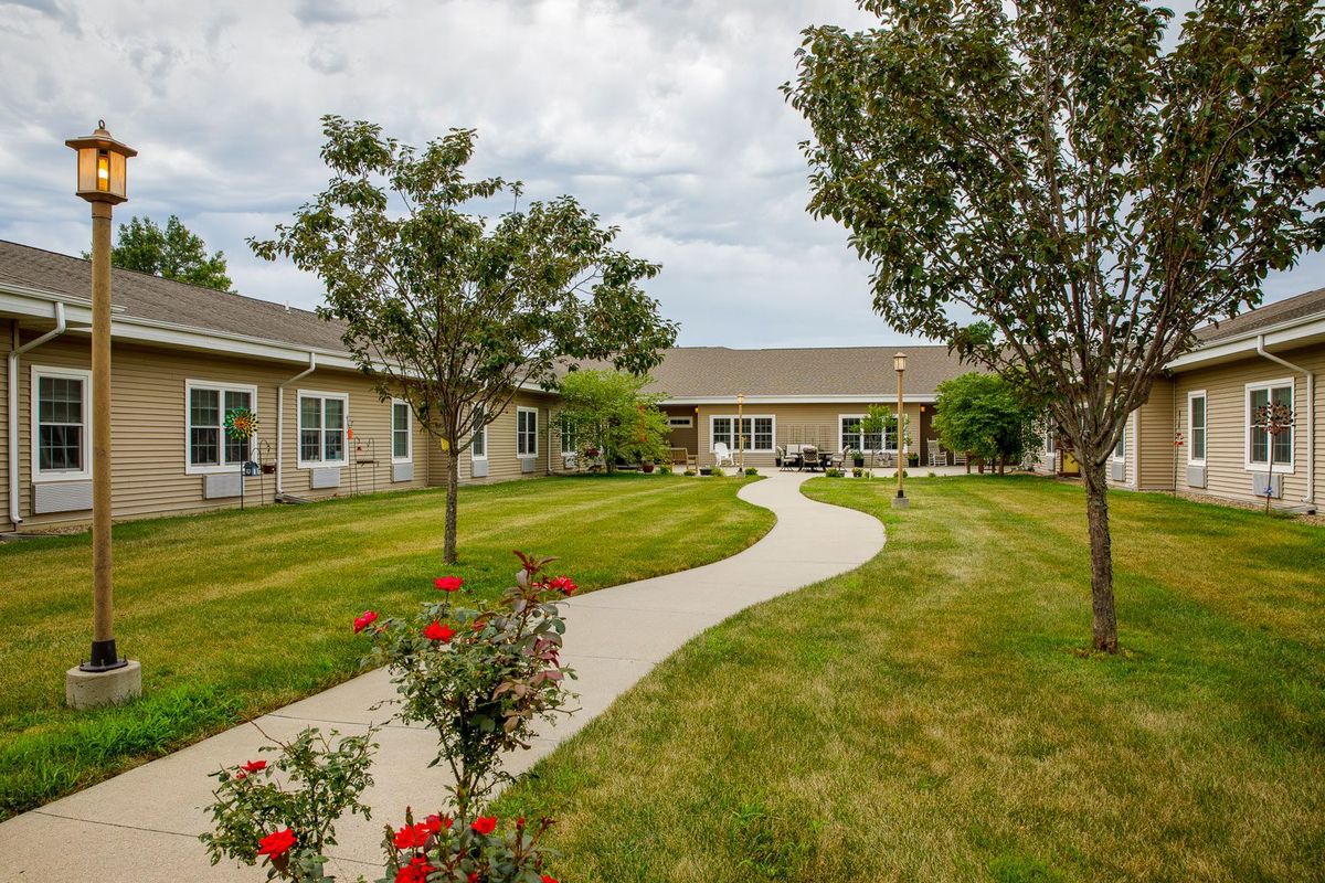 A peaceful garden with a walkway leading to a building surrounded by trees and well-maintained grass.
